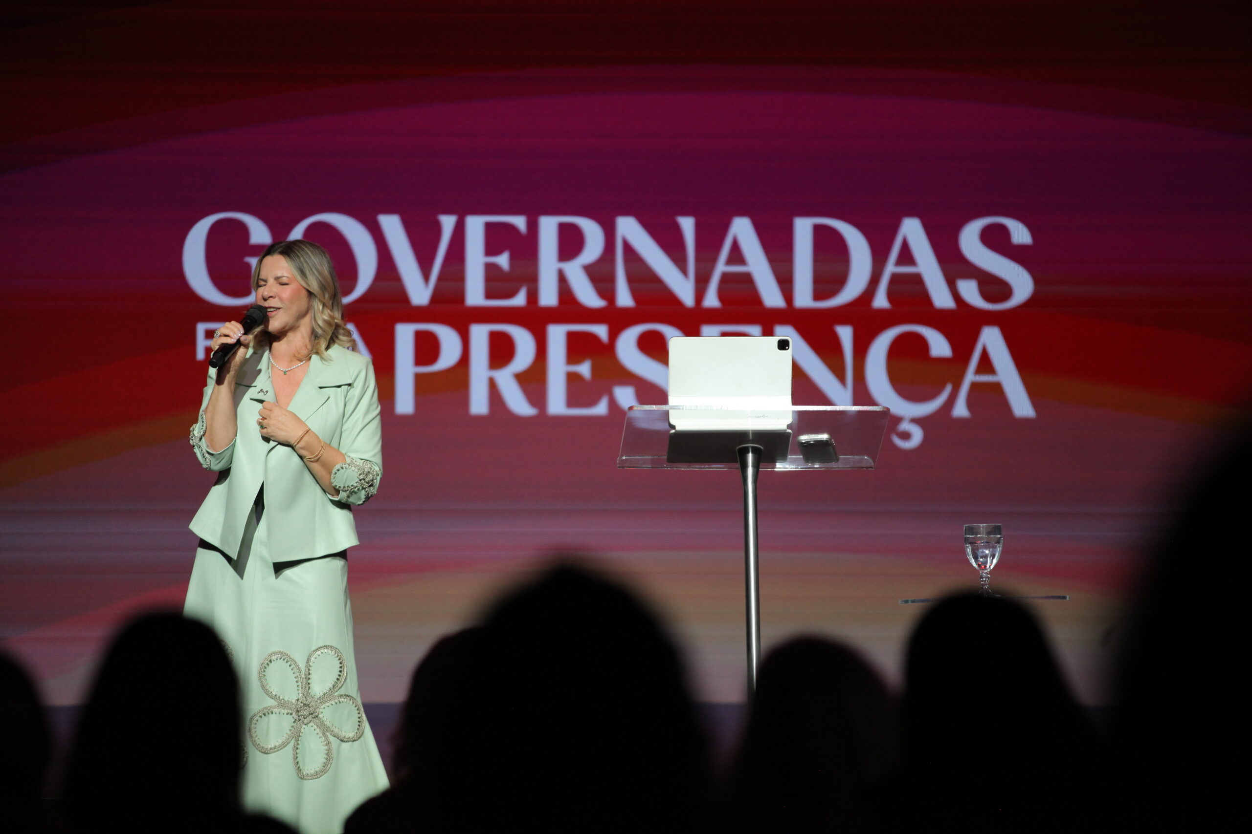 Bispa Dirce Carvalho no palco da Conferência Modeladas Mais 2026 com a plateia em primeiro plano