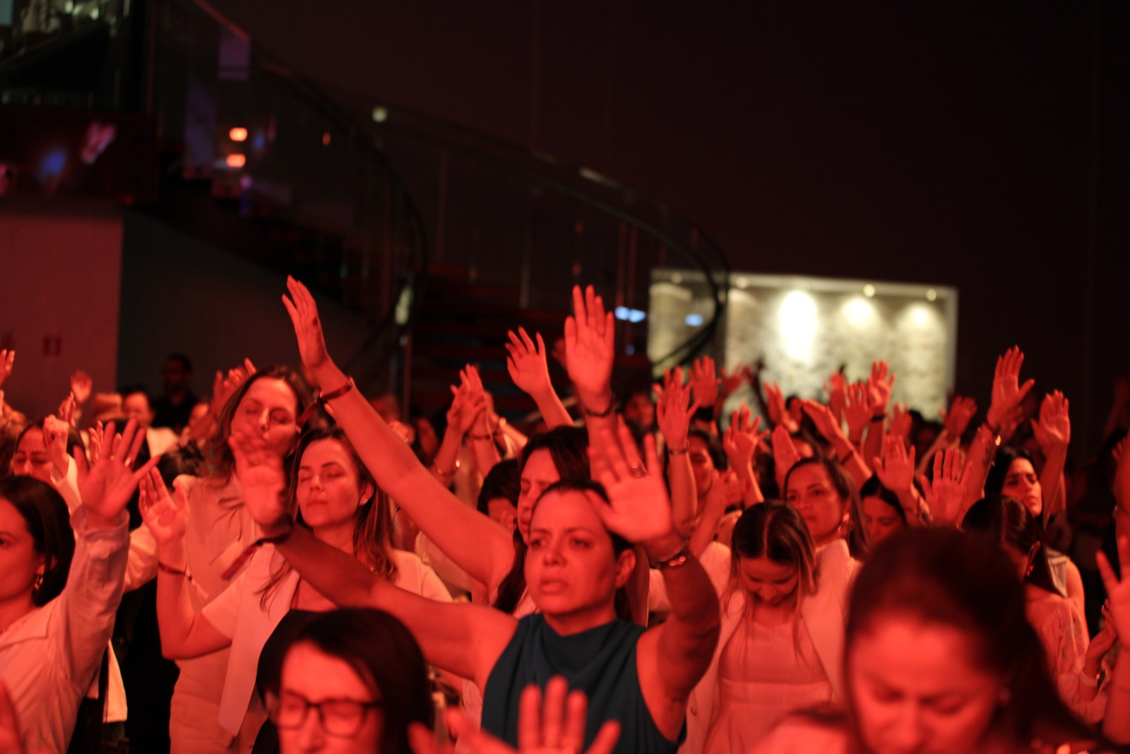 Plateia do Modeladas Mais 2026 com as mãos levantadas durante a oração
