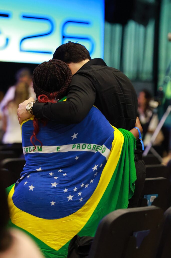 Duas pessoas se abraçam, uma delas com a bandeira do Brasil nas costas
