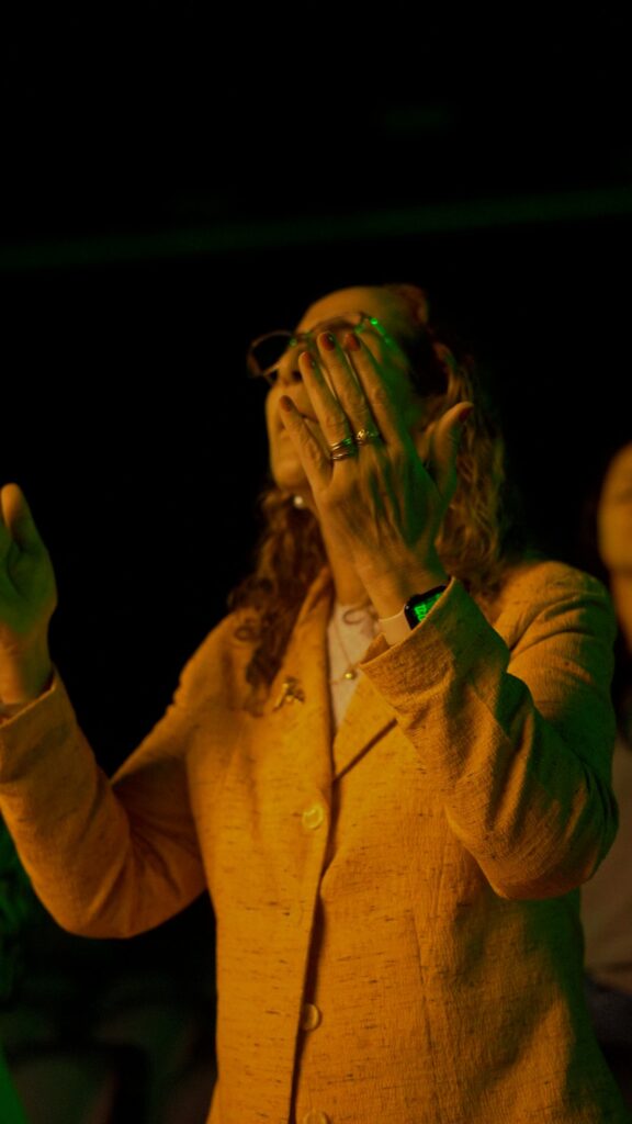 Mulher de blazer amarelo em adoração, com as mãos no rosto