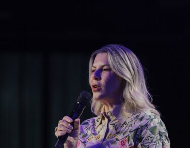 Bispa Dirce Carvalho, de camisa florida, fala ao microfone durante a pregação na Conferência Global 2026