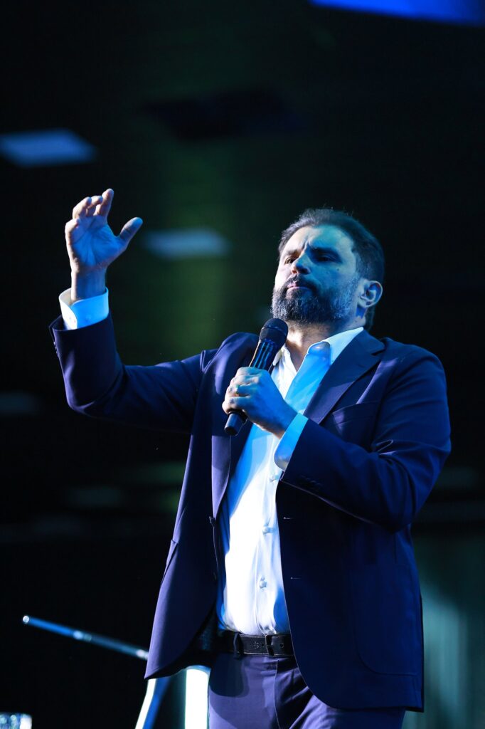 Bispo JB Carvalho levanta a mão enquanto fala ao microfone