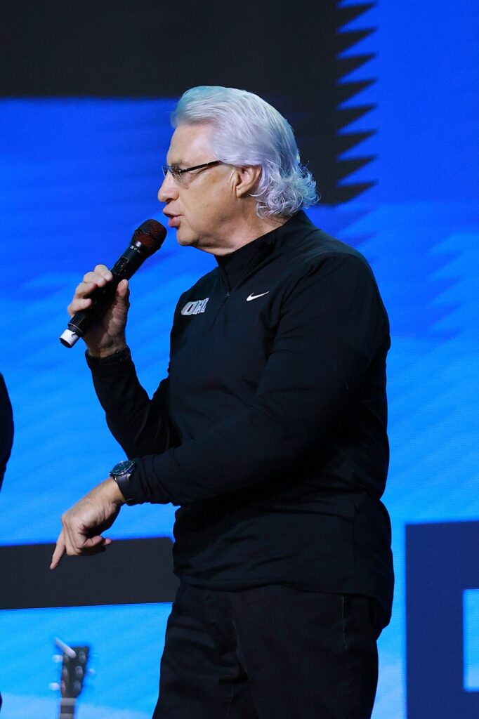 Charles Scott aponta para o público enquanto fala ao microfone