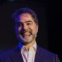 Victor Sorrentino sorri no palco, de terno risca de giz e microfone de lapela, na Conferência Global 2026